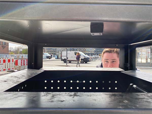 A man looking at a Nordsense sensor inside a public street bin.