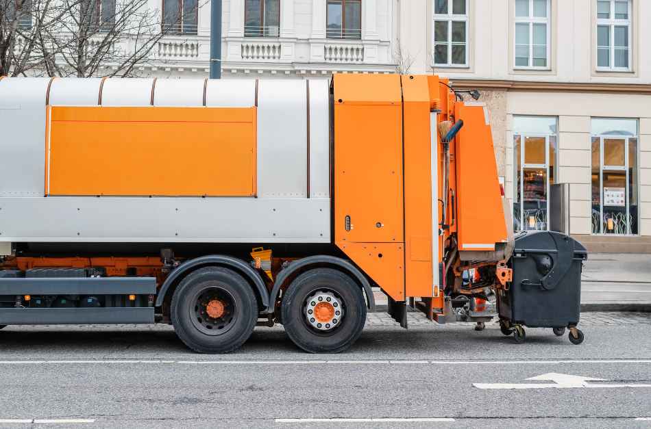 Orange garbage truck servicing a bin